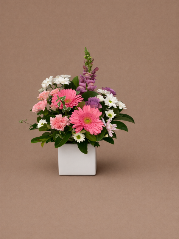 Mother’s Day flower arrangement with pink gerberas, carnations, white daisies and purple blooms in a white vase