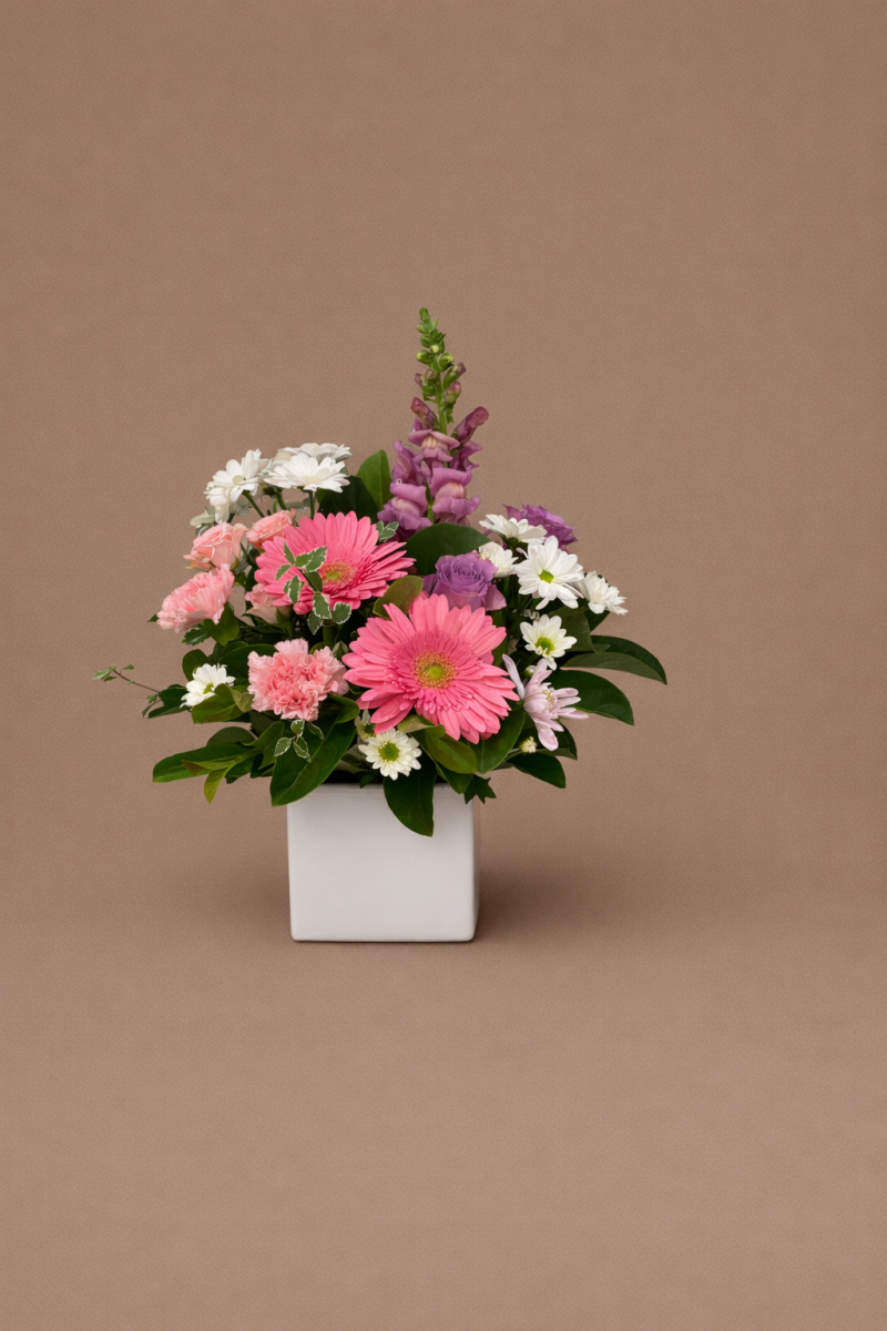Mother’s Day flower arrangement with pink gerberas, carnations, white daisies and purple blooms in a white vase