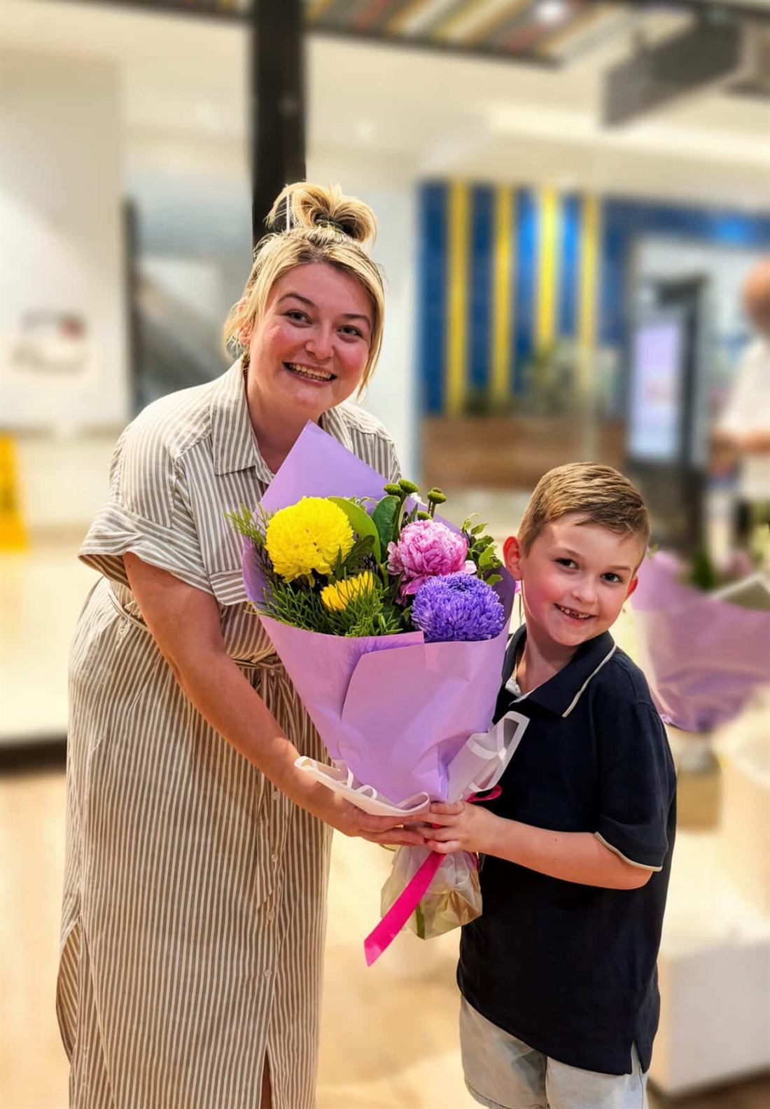Our third-place Mother's Day giveaway winner with her six-year-old son, holding the purple-wrapped bouquet they collected together at Australia Fair, Southport.