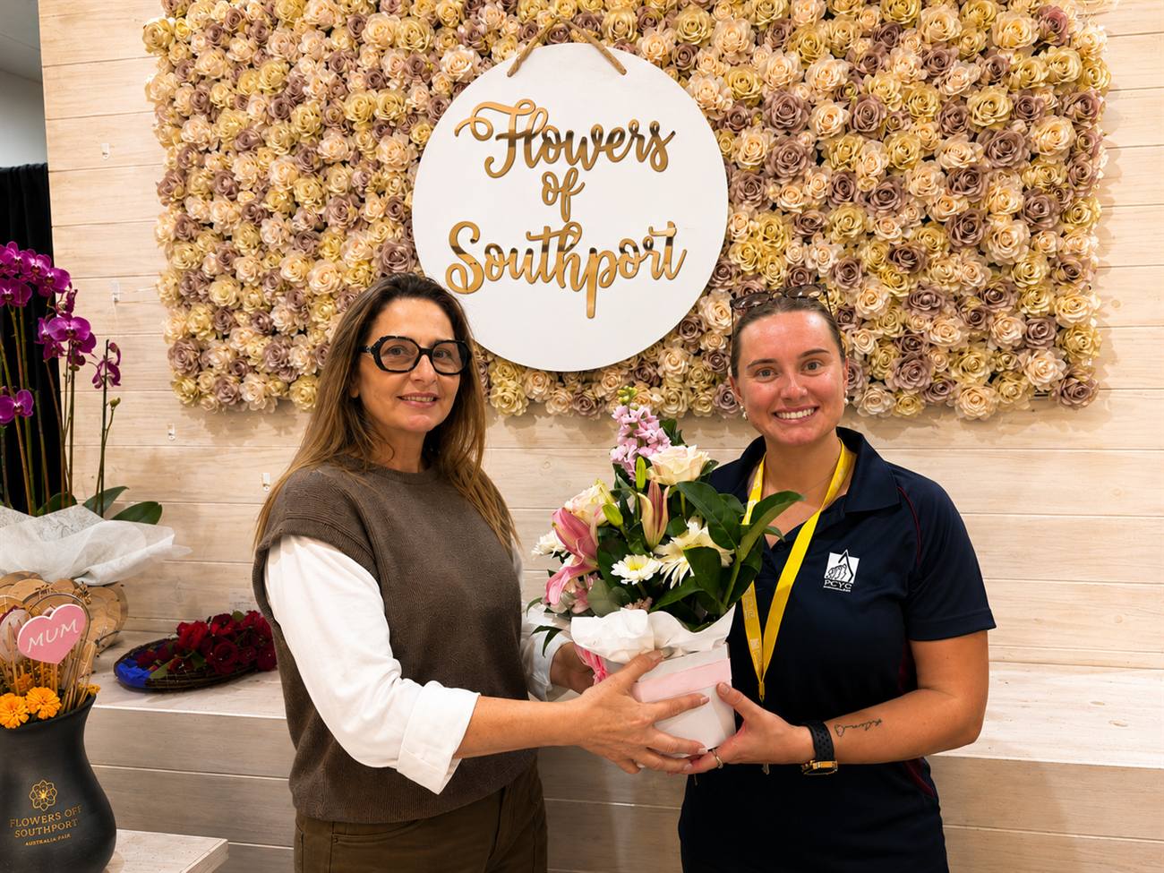 Carolina from Flowers of Southport hands the first month's Gymnast of the Month bouquet to Billee Ruckwood, Gymnastics Program Leader at PCYC Queensland, at the Australia Fair Southport shop.