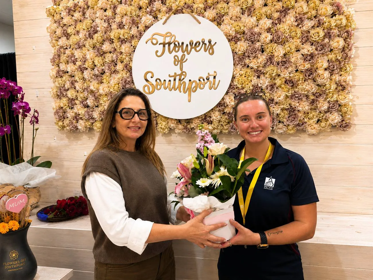 Carolina from Flowers of Southport hands the first month's Gymnast of the Month bouquet to Billee Ruckwood, Gymnastics Program Leader at PCYC Queensland, at the Australia Fair Southport shop.